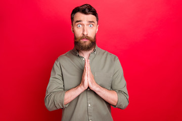 Photo of praying hoping man seeing something disappointing while isolated with red background