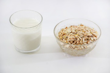 glass of milk and dry oatmeal isolated on white background