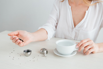 Obraz na płótnie Canvas Young beautiful girl brews tea in a useful reusable metal strainer