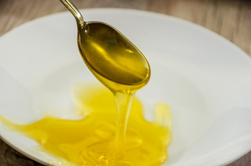 a spoonful of sweet, fresh honey. Honey in a spoon on a white plate background. Close-up.