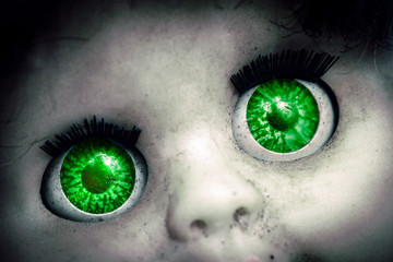 macro image of a old spooky doll with green eyes 