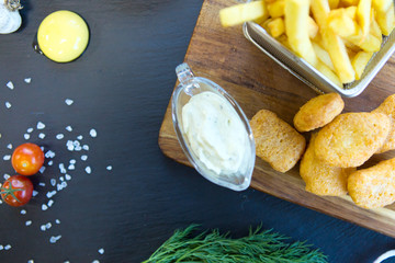 Chicken Nuggets and Chips with sause on wooden cutting board