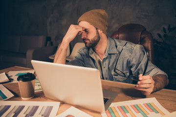 Photo of stressed guy working late at night hold nose bridge dressed in casual outfit sit modern...