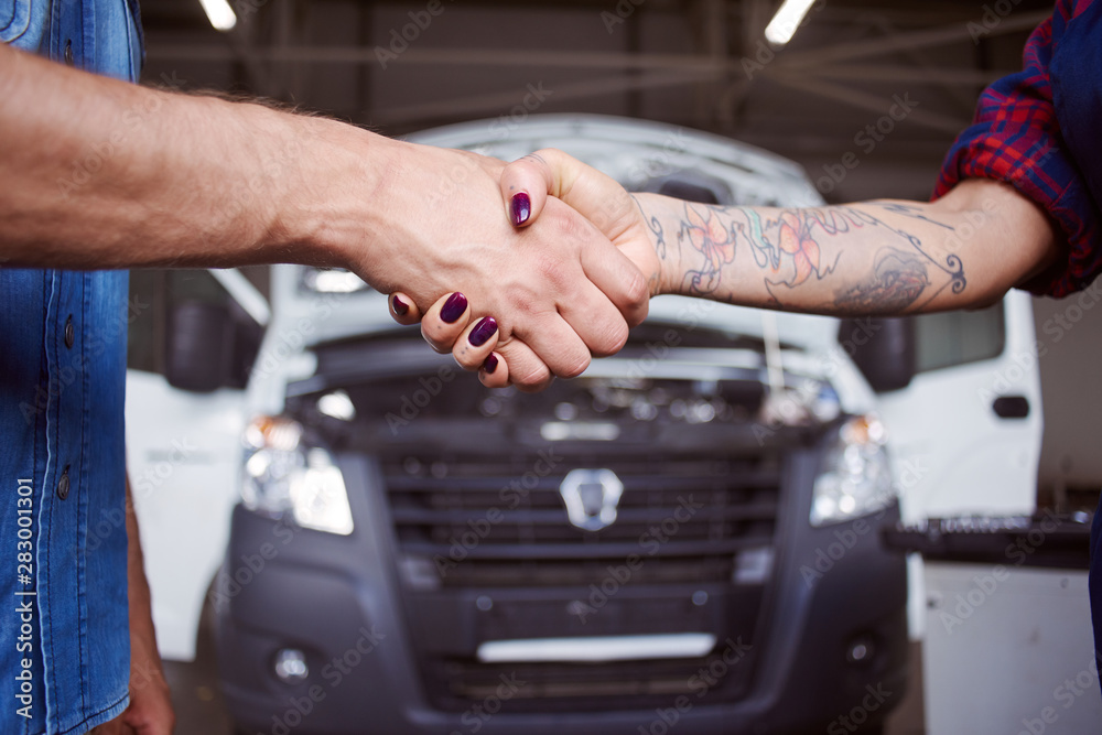 Wall mural Car mechanic and car owner shakes hands in a close up.