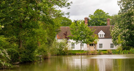 Fototapeta premium Traditional white cottage with its own tree lined lake, Norfolk, UK.