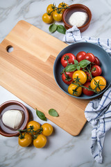Rote und gelbe Tomaten mit Mozzarella und Basilikum auf Holz Brett mit Geschirrtuch
