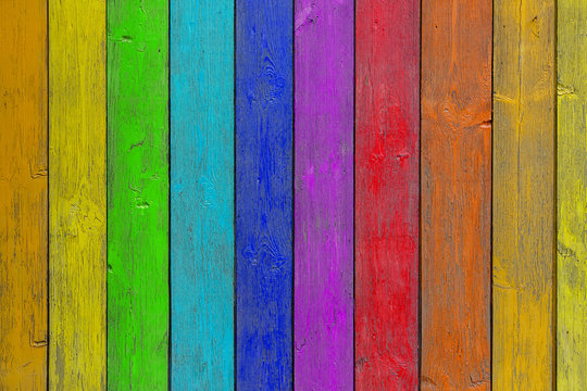 Close-up of a   rainbow wooden  wall  or fence painted a very long time and the paint peeled off.  Fun background for kids decor and design.