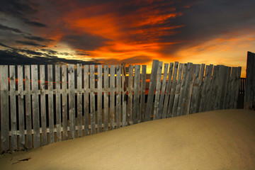 wooden fence in a dune with orange sky
