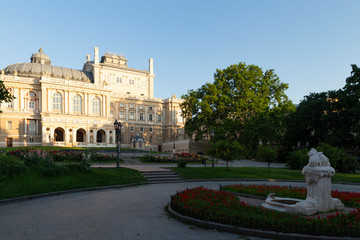 Naklejka premium Ukraine, Odessa, 13th of June 2019. Side view of the national academic opera building and the park with the sculpture fountain youth during a sunny day