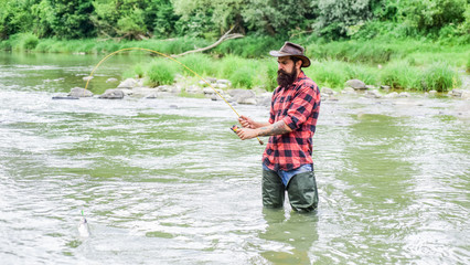 On The Fly Fishing hobby and sport activity. bearded fisher in water. summer weekend. Happy fly fishing. fisherman show fishing technique use rod. mature man fly fishing. man catching fish