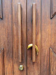 Yellow banana peel resting on a handle of a wooden door of a building
