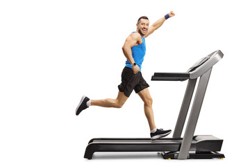 Young muscular man running on a treadmill and gesturing with hand