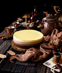 Beautiful still life with homemade delicious three chocolates cheese cake on wooden stand on rustic table