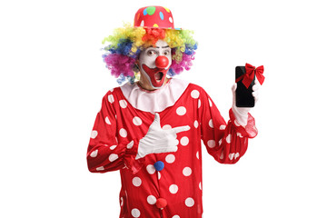 Happy smiling clown holding a mobile phone with a red bow and pointing at it