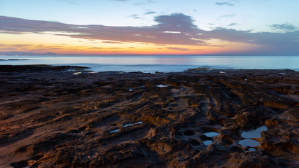 Just before dawn on the rocky coast of La Mata near the Spanish town of Torrevieja. On the horizon a beautiful dawn over the Mediterranean Sea.