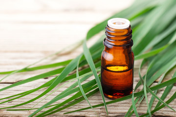 lemongrass essential oil in the bottle, with fresh lemongrass leaves, on the wooden table