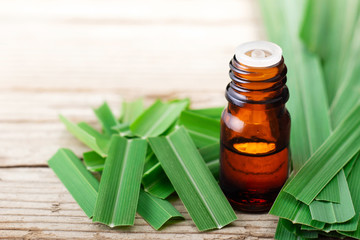 lemongrass essential oil in the glass bottle, with fresh lemongrass leaves, on the wooden board