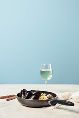 delicious Italian pasta with seafood served in frying pan with white wine isolated on blue