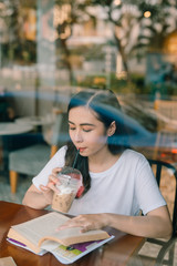 Picture of young pretty woman sitting at the table in cafe and reading book.