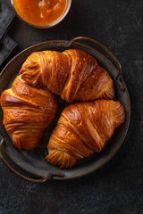 Freshly baked croissants on vintage tray. heap of Freshly baked croissants on dark background. French patisserie