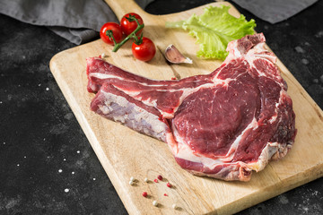 Raw beef meat on wooden Board on dark background