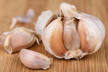 Head of garlic and several cloves of unpeeled garlic on a wooden background.