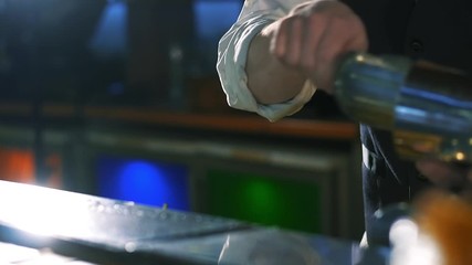 Close-up of a bartender putting ice into a shaker