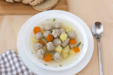 Soup with meatballs and vegetables on the table top view. Bowl of soup with meat. Healthy eating.