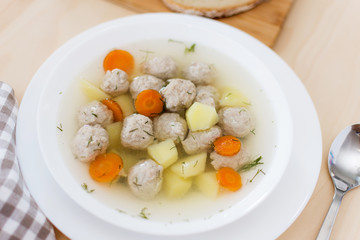 Soup with meatballs and vegetables on the table top view. Bowl of soup with meat. Healthy eating.