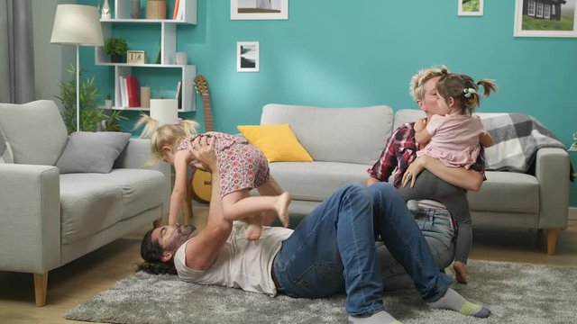Dad, mom and two daughters play a monster at home on the floor