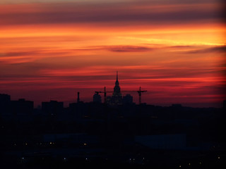 Naklejka premium Building crane silhouettes on a moody sunset sky