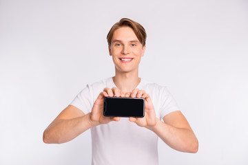 Photo of sales manager guy holding new telephone model wear casual t-shirt isolated white background
