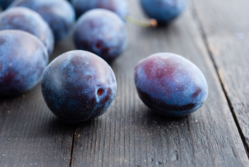 plums on black wood table, front view
