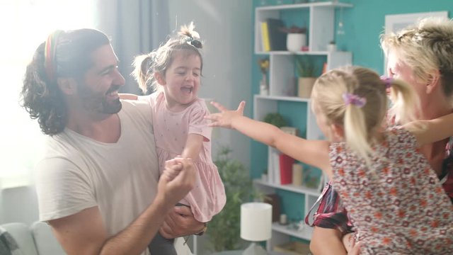 Mom And Dad Are Dancing With Daughters In Their Arms At Living Room