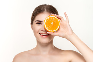 Close-up portrait of a happy beautiful young girl holding half of oranges close to face isolated over white background.