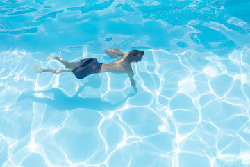 Kid diving in a swimming pool in summer