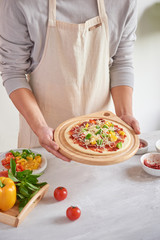 Raw pizza with ingredients in the background