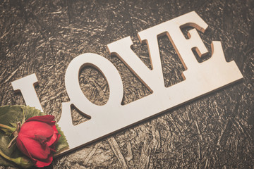 Word love with red rose on black background