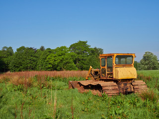 Obraz premium An Old Bulldozer in a Farm Field near Letham in Angus, Scotland, Its yellow Cabin rusted with age. Going nowhere.