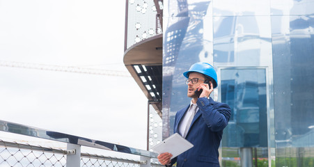 Real estate developer in helmet. New office construction. Confident business men or architect in front of office building.