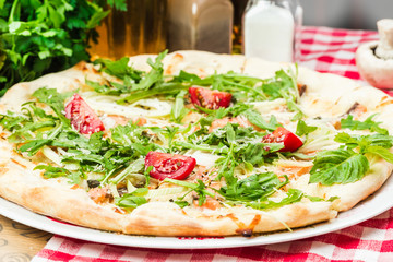 Homemade italian pizza, fresh cherry tomatoes and basil, arugula served on wooden board