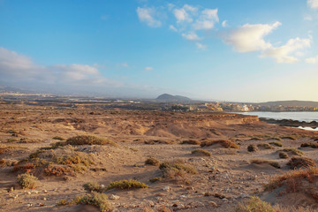 Fototapeta na wymiar Early morning views from Montana Roja Special Natural Reserve, one of the best samples of inorganic sand habitats on the island of Tenerife towards the quaint town of El Medano, Canary Islands, Spain