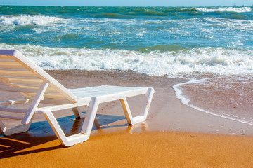 White lounge chair standing on a sandy beach by the sea
