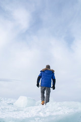 Man walking on broken ice and looking forward in Lake Baikal, Russia, landscape photography