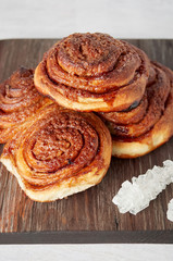 Obraz na płótnie Canvas Homemade sweet cinnamon buns with sugar on wooden cut board
