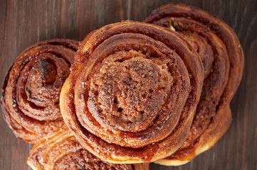 Homemade sweet cinnamon buns with sugar on wooden cut board
