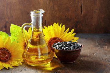 Glass bottle of sunflower oil with seeds and flowers. Close up view with copy space