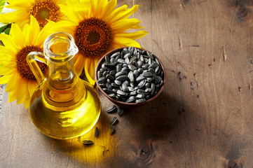 Glass bottle of sunflower oil with seeds and flowers. Close up view