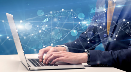 Businessman typing on laptop with linked reports charts grapghs around
