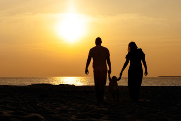 silhouette of a family with a child by the sea at sunset